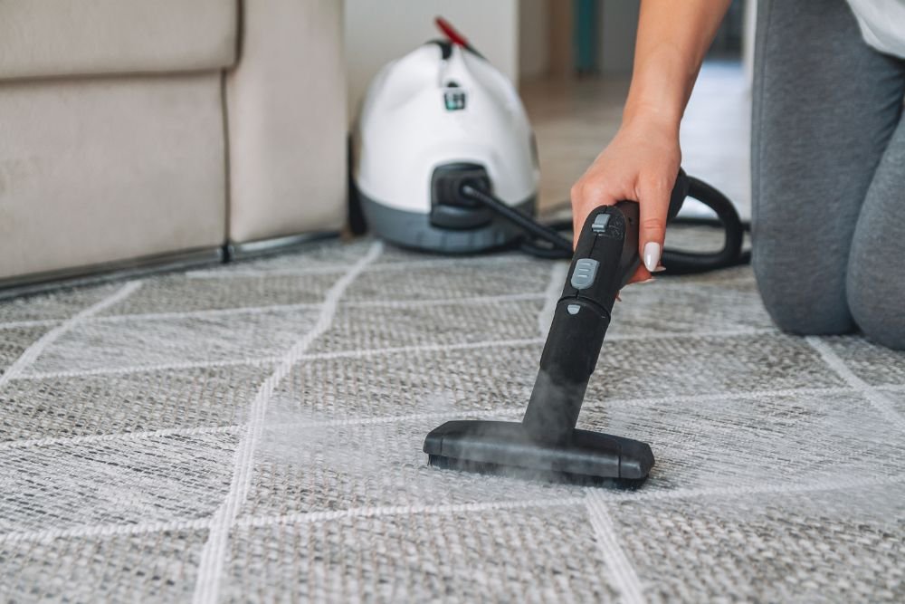 A woman using a steam cleaner on a carpet, representing protection and prevention services in Columbia, SC.
