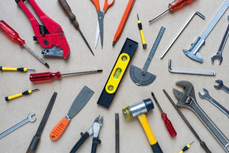 Various hand tools, including saws and drills, are organized on a table, highlighting their diverse functions and designs.