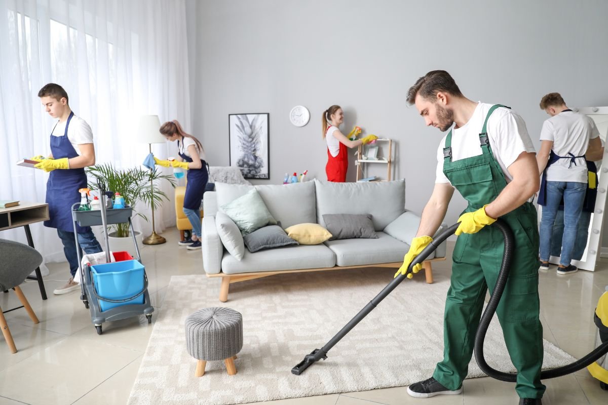 A group of individuals using vacuums to clean a room, demonstrating teamwork and effort in maintaining cleanliness.