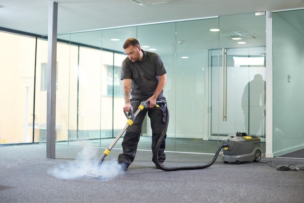 A man operates a vacuum cleaner on a carpet, focusing on removing dirt and debris.